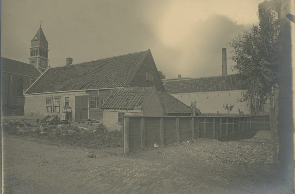 Deze foto is gemaakt op de hoek van het Smedemanplein, met uitzicht op de Dorpskerk. Hoewel de huizen op elkaar lijken, is de huidige woning gebouwd in 1976. Ook de Dorpskerk is kort na de foto uit 1924 veranderd: in 1925 is de kerk uitgebreid met zijbeuken (links zichtbaar op de foto van nu). In 1927 werd de toren beschadigd door blikseminslag en in 1928 vervangen door de huidige toren.